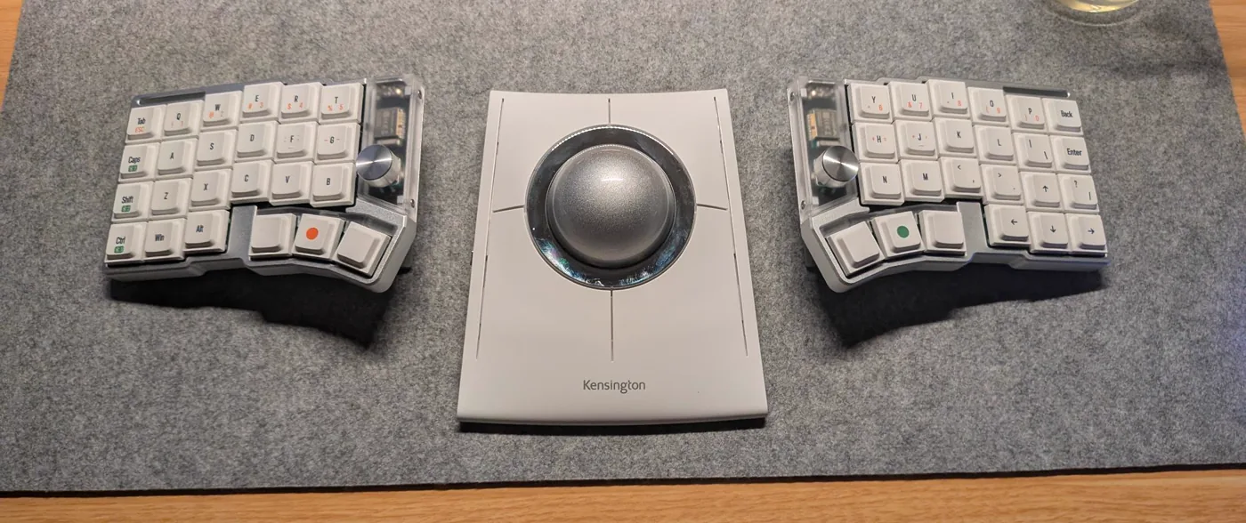 Top-down view of the two keyboard halves spread apart with a Kensington SlimBlade trackball centred between them
